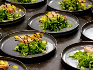 Elegant gourmet dish carefully plated with arugula, mango, and balsamic glaze.
